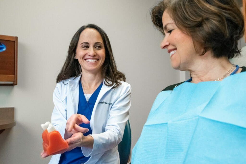 cosmetic dentist in Highland Village showing patient how to clean teeth