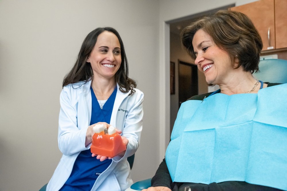 Dr. Richardson, a restorative dentist in Highland Village, showing a patient a dental implant