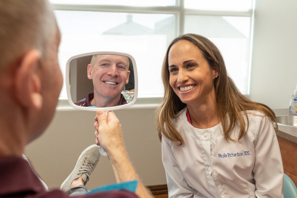 Smiling patient admiring their restorative dental work done by Dr. Richardson